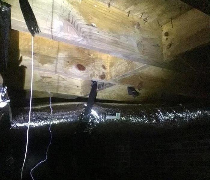 Wooden joists in a crawl space are cleaned of mold