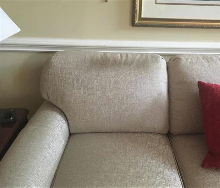 A light colored couch has a dark stain along the top where heads rest