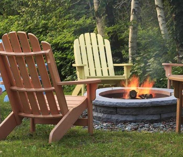 Adirondack chairs surround a cinderblock fire pit that is safely burning 
