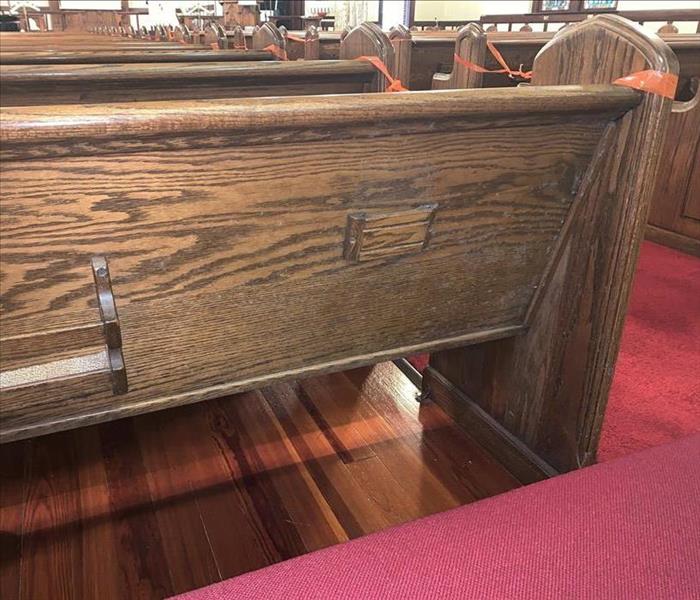 Mold growth appears on the back of a wooden church pew