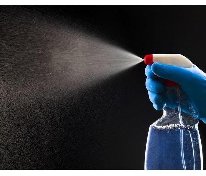 A spray bottle is squeezed, emitting a mist into the air 